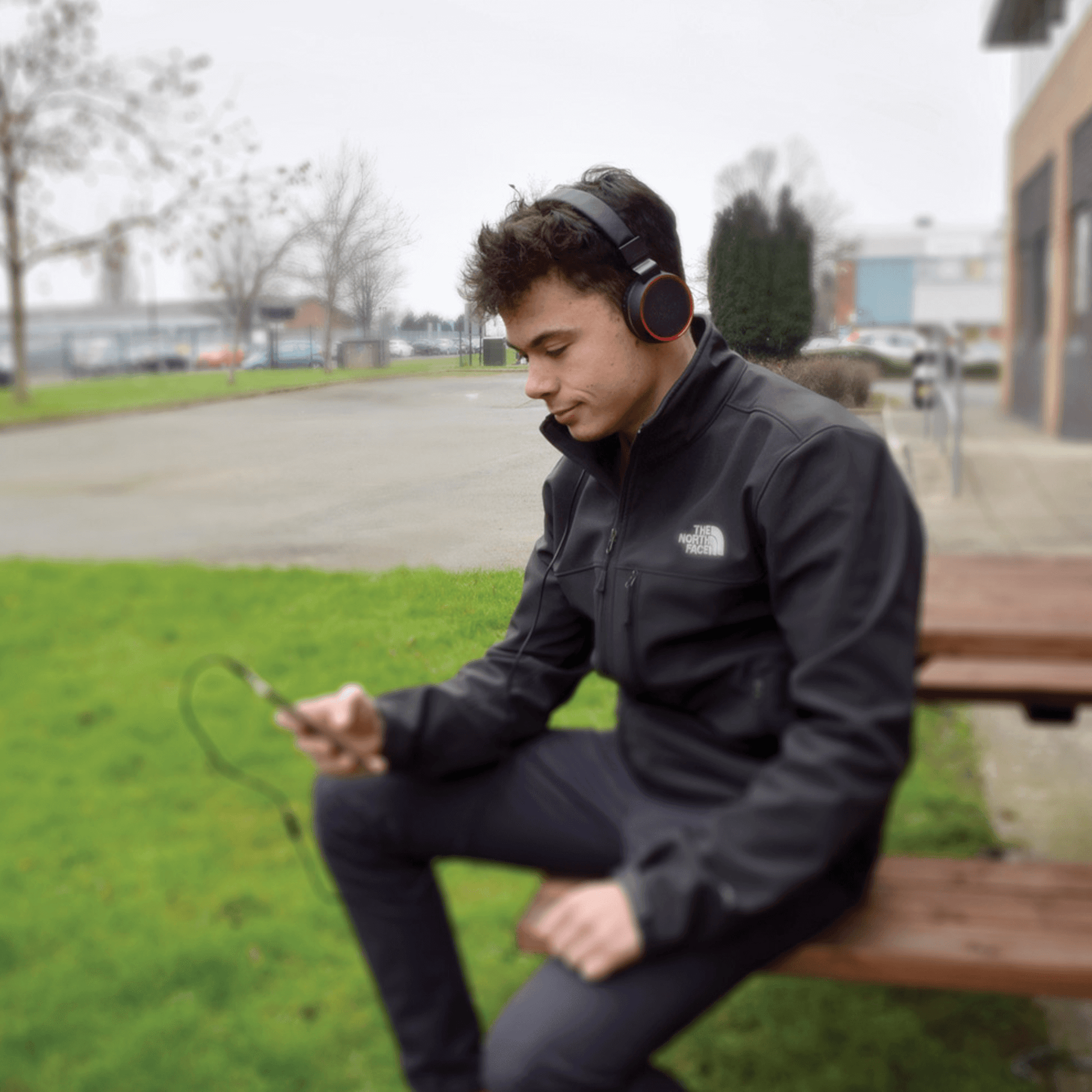 boy looking at phone wearing headphones